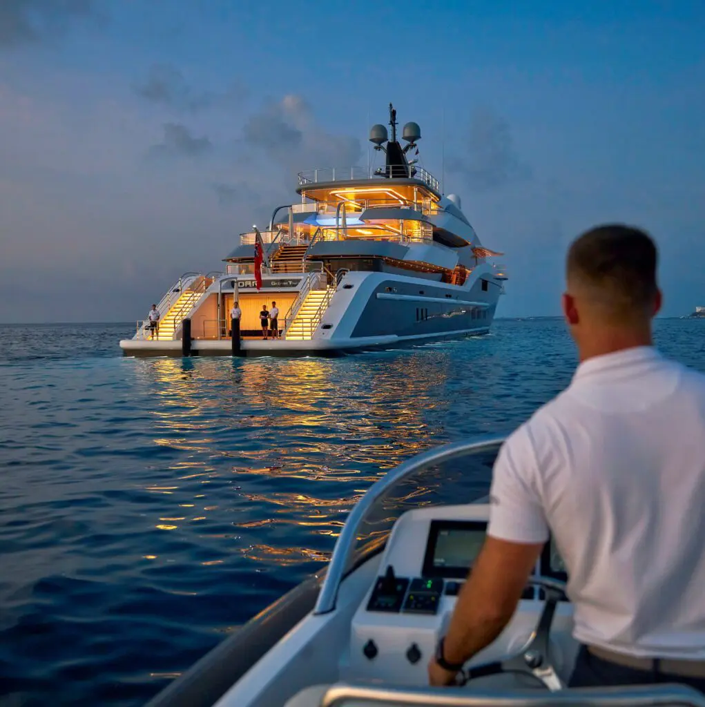 A man driving a boat towards a large yacht.