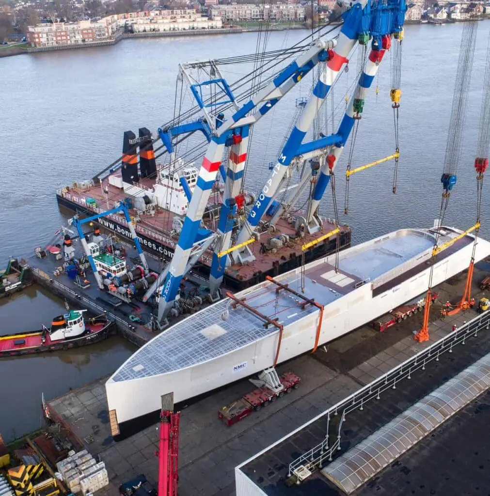 A large white yacht being lifted by cranes.