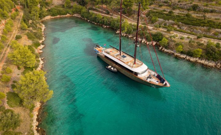 A large sailing yacht anchored in a sheltered bay.