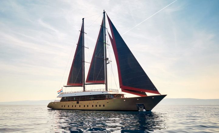 A large sailing yacht with black sails on the sea.