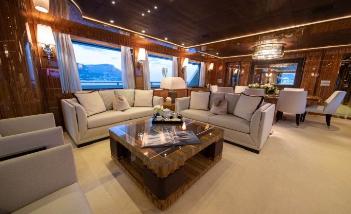 Luxurious yacht interior with sofas and dining table.