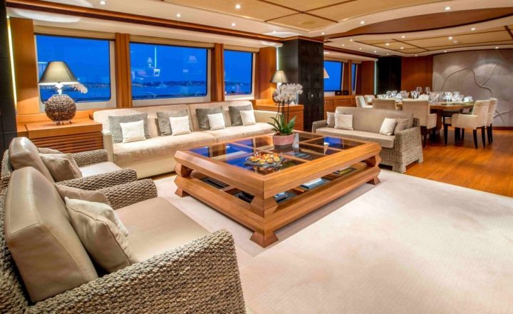 Luxury yacht interior with sofas and dining table.