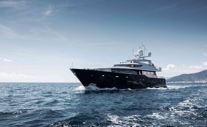 A large black yacht is cruising on the open sea.